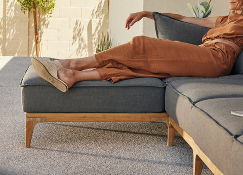 Woman lounging on sofa with feet up on ottoman outdoors
