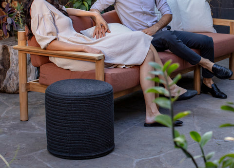 Round ottoman alongside an outdoor sofa with a young couple sitting on it